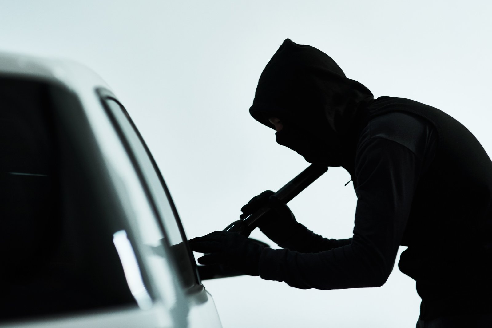 Hes looking inside the car for some valuables to steal